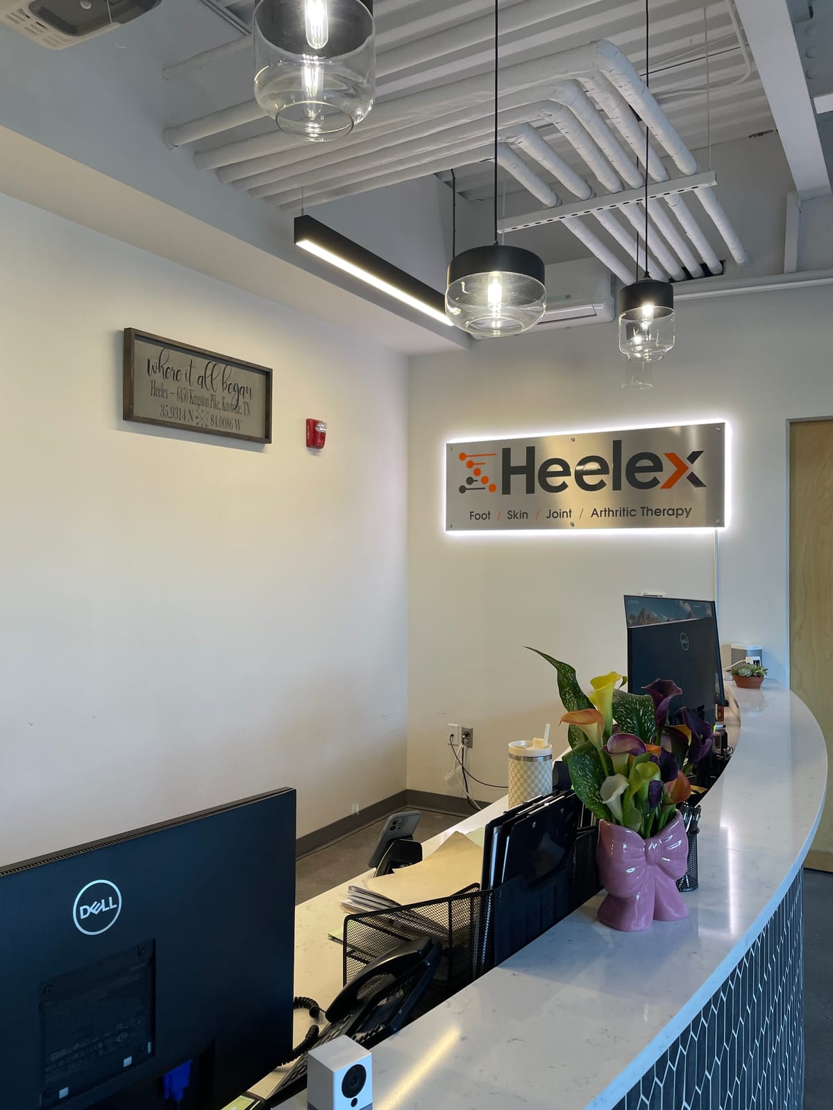 Interior reception area of the Heelex clinic in Knoxville, Tennessee, with the backlit Heelex Foot, Skin, Joint, and Arthritic Therapy sign.