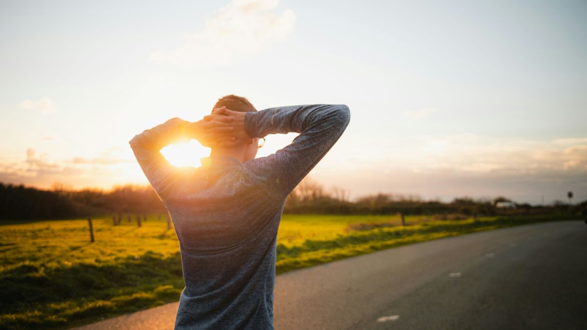 A runner mid-stride in warm outdoor light, viewed from behind.