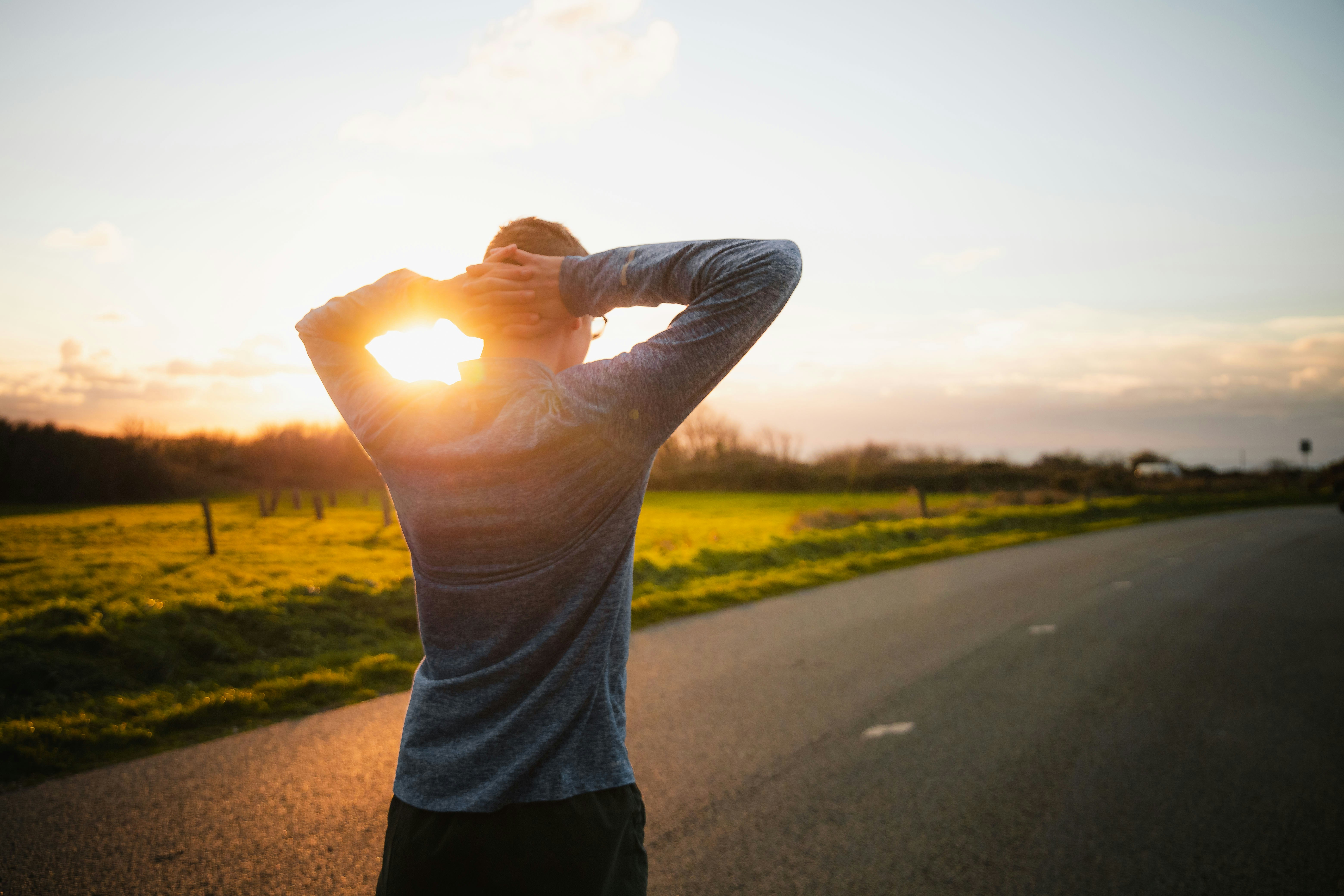 A runner mid-stride in warm outdoor light, viewed from behind.